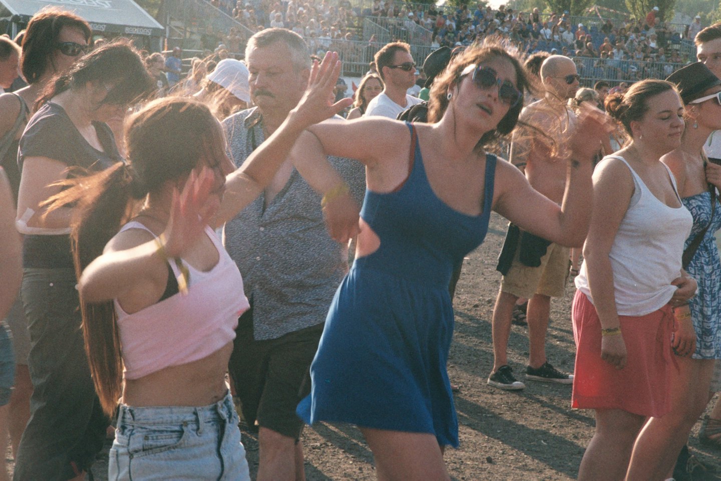 Three women dance together at an outdoor music festival.